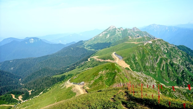 Man stands with Russian flag on the peak of Black Pillar mountain, Krasnaya Polyana, Sochi Russia