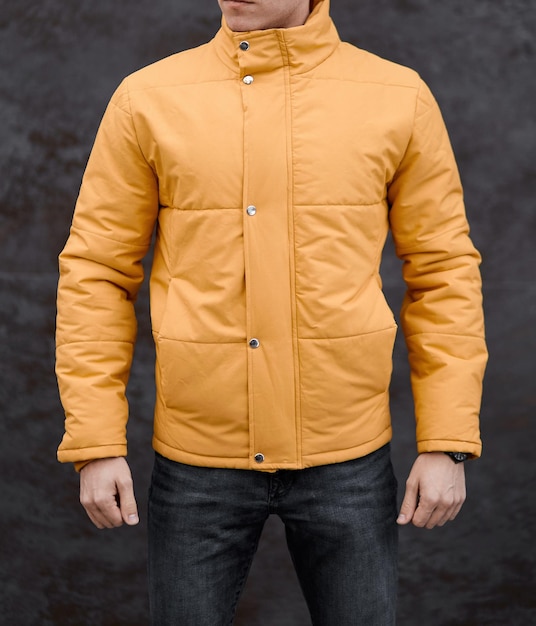 Man stands in yellow winter jacket on grey background