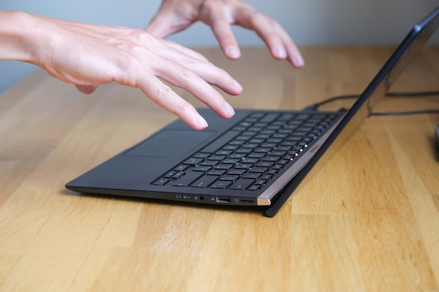 Man starts working on a laptop, holds his hands over the keyboard