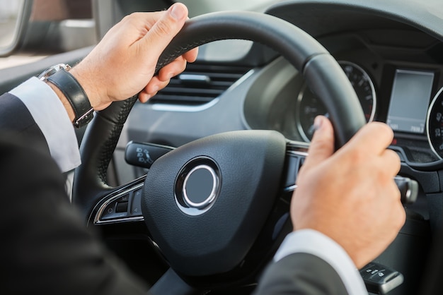 Man steering wheel. Close-up of man in formalwear driving car