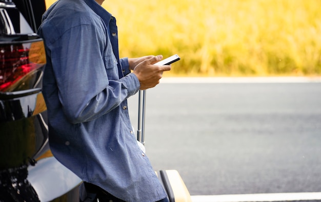 man stood in the car with his mobile phone and luggage