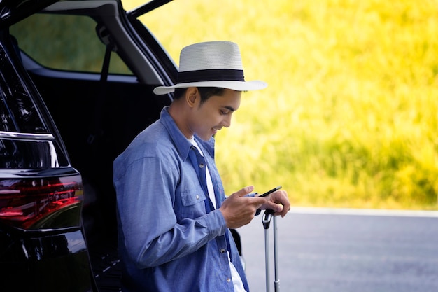 man stood in the car with his mobile phone and luggage