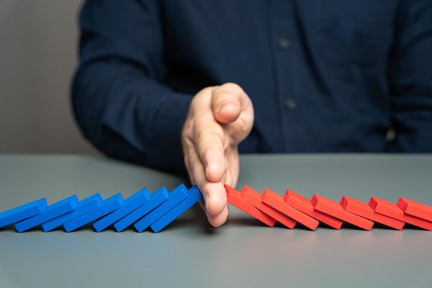 A man stops two domino chains from colliding