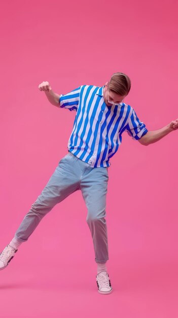 Photo man in striped shirt dances by pink background