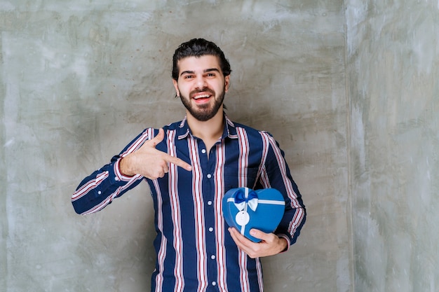 Man in striped shirt holding a blue heart shape gift box