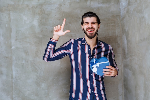 Man in striped shirt holding a blue heart shape gift box