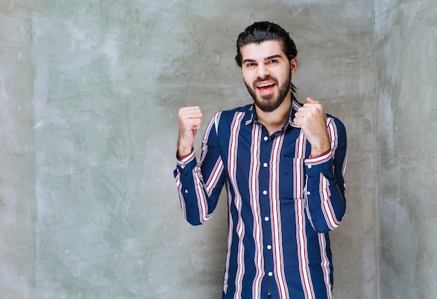 Man in striped shirt showing her fists and feeling strong.