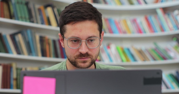 Man student preparing exam and learning lessons in library making research on laptop and browse internet Self education concept