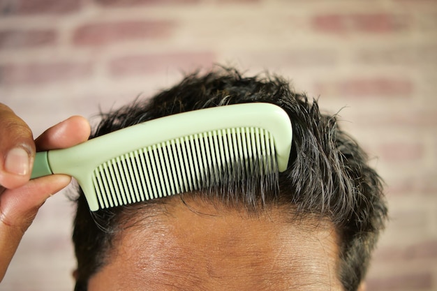 Man styling hair with comb close up