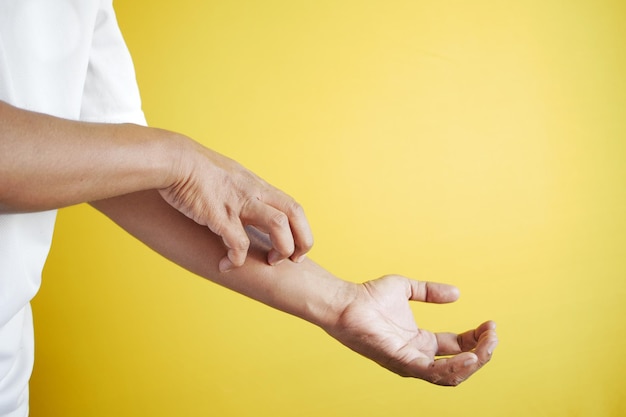 Man suffering from itching skin against yellow background