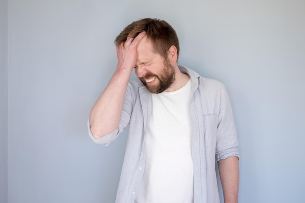 man suffers lot from a headache or is trying to remember something he touches forehead and grimaces