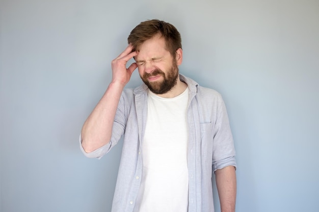 man suffers severe headache or is trying to remember something he touches his head and grimaces