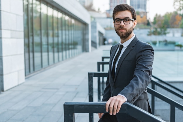 Man in a suit in eyeglasses against the background of an office building.