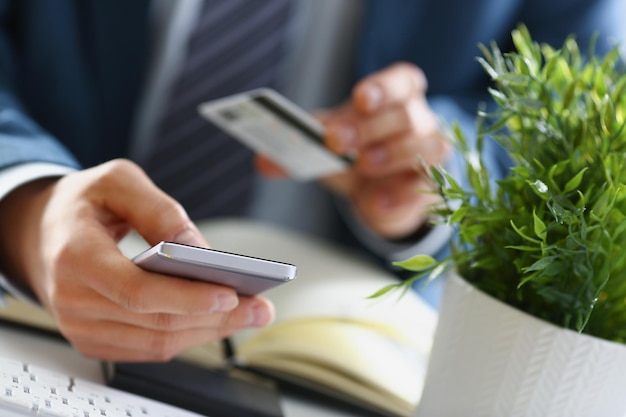 Man in suit hold credit card and mobile phone make transfer online payment