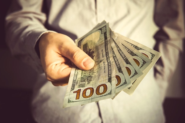 Man in a suit holding fan of dollar banknotes