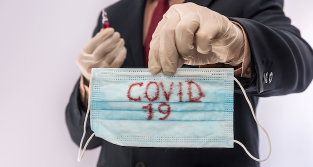 Man in suit holding medical protective mask with text covid19.