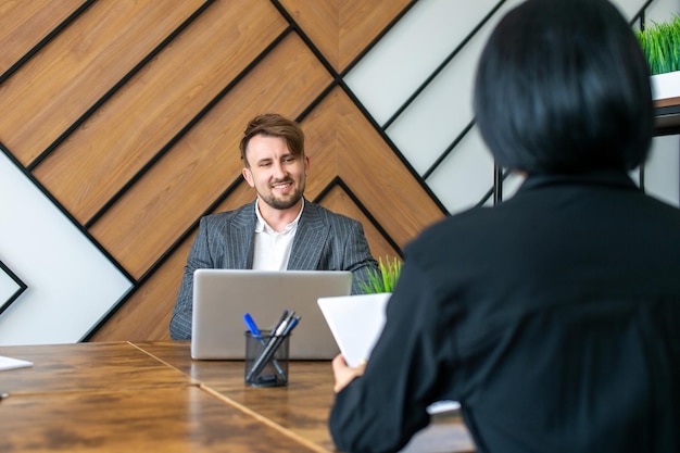 A man in a suit is sitting at his workplace and laughing with colleagues