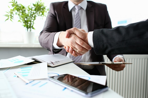 Man in suit shaking hand as greeting at office