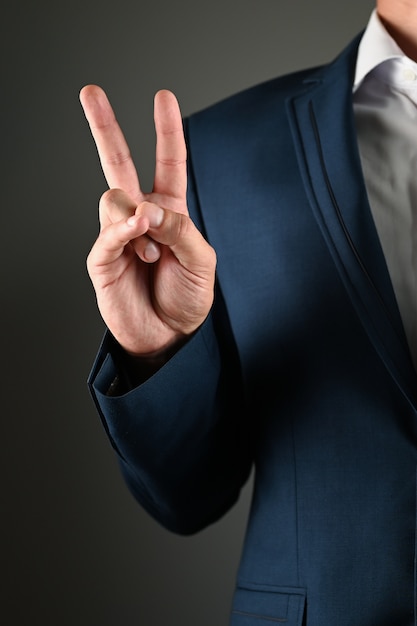 Man in suit shows peace symbol with his hand