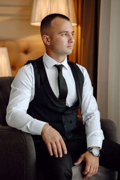 a man in a suit sits in a chair in front of a lamp