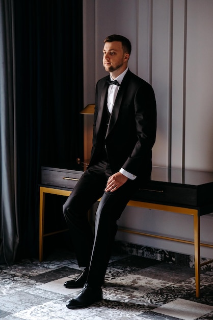 Photo a man in a suit sits on a table in front of a black and gold table