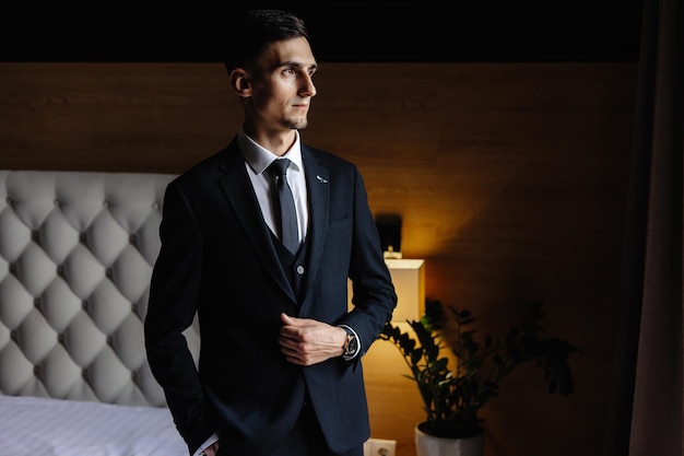 Photo a man in a suit stands in front of a bed with a lamp on it