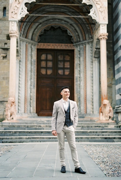 Man in a suit stands in front of the entrance to the church Bergamo Italy