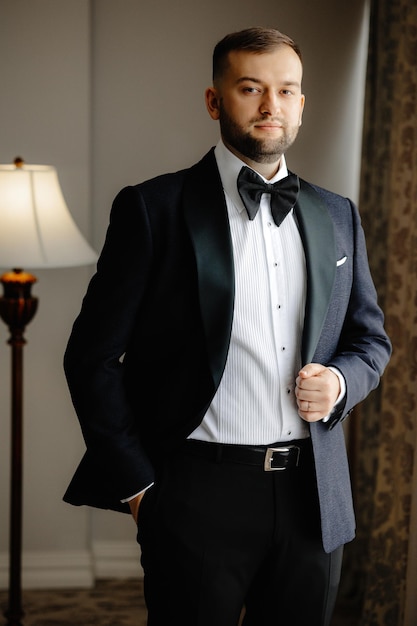 A man in a suit stands in front of a lamp that says " the groom ".