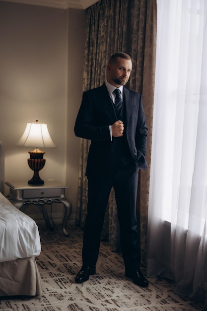 Photo a man in a suit stands in front of a window with a curtain that says quot man quot