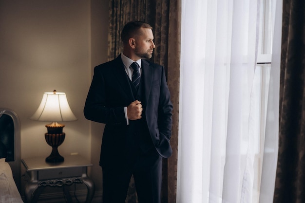 Photo a man in a suit stands in front of a window with a curtain that says  the word  on it