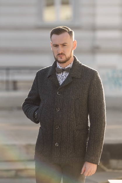 Man in a suit and sweater poses on the street