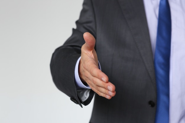 Man in suit and tie give hand as hello in office