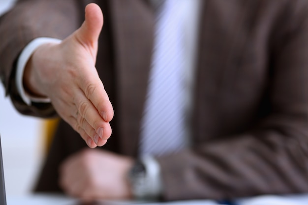 Man in suit and tie give hand as hello