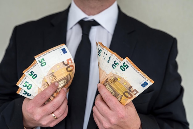 Man in suit with good taste holds euro banknotes for big purchase Big purchase concept