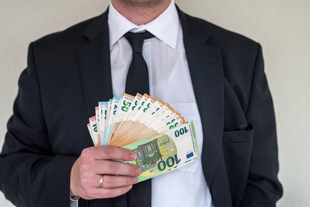 Man in suit with good taste holds euro banknotes for big purchase