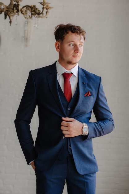 a man in a suit with a red tie and a watch on his left hand