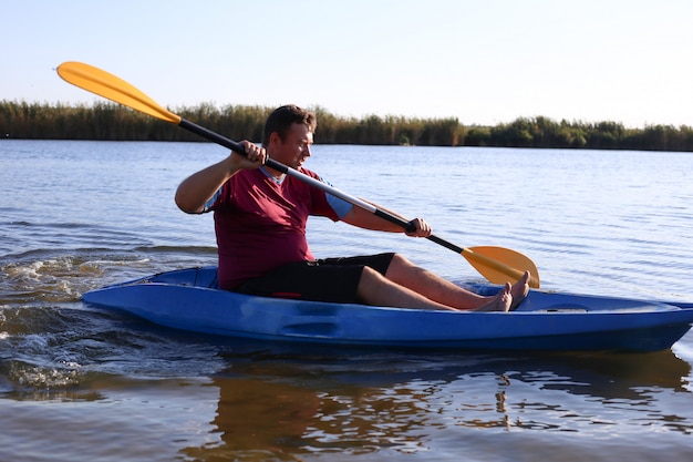 A man in summer swims on the river in a kayak