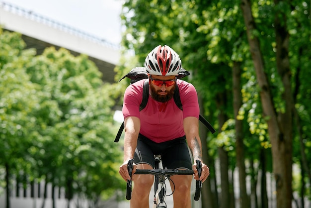 Man in sunglasses speeds along the road against a background of summer park Man with a bicycle hobby rides in the park