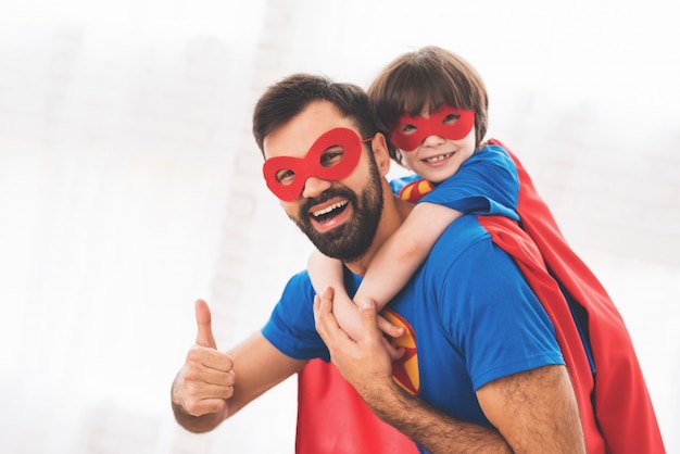 A man in a superhero costume with a child on his shoulders.