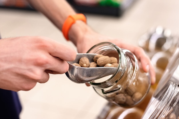 Man in a supermarket with jar taking nuts