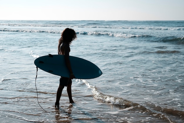 Man Surfer Sitting at Surfboard on Sand Beach