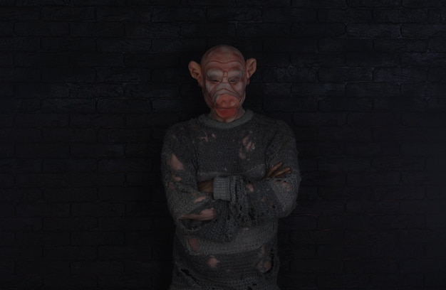 A man in a sweater with a red face stands in a dark room with a black background.