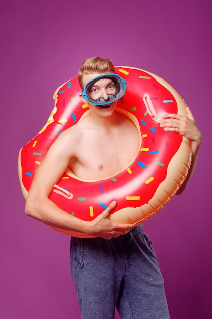 Man in swimming circle and face mask for diving on purple background