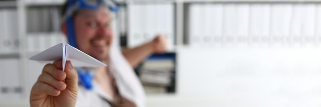 Man in swimming goggles plays and launches paper airplane in office