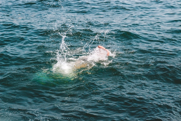 Man swimming in the sea, splashing water.