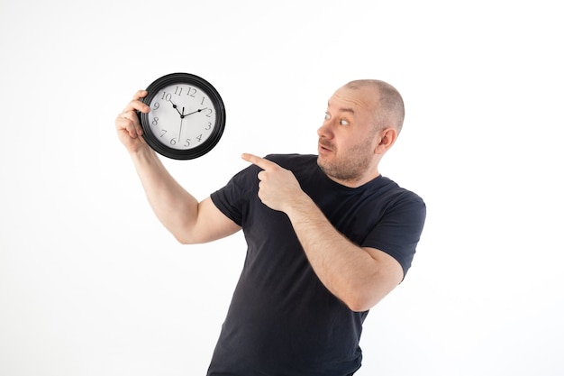 A man in a T-shirt holds a large clock