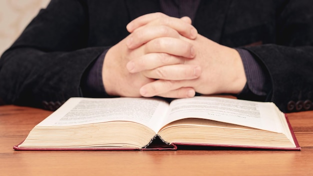 A man at the table is reading the Bible Man near the Bible during prayer