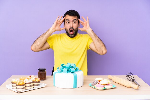 Man in a table with a big cake with surprise expression