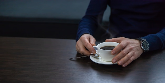 A man at the table with a cup of coffee