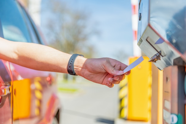 The man takes a parking ticket when entering the paid parking lot by car